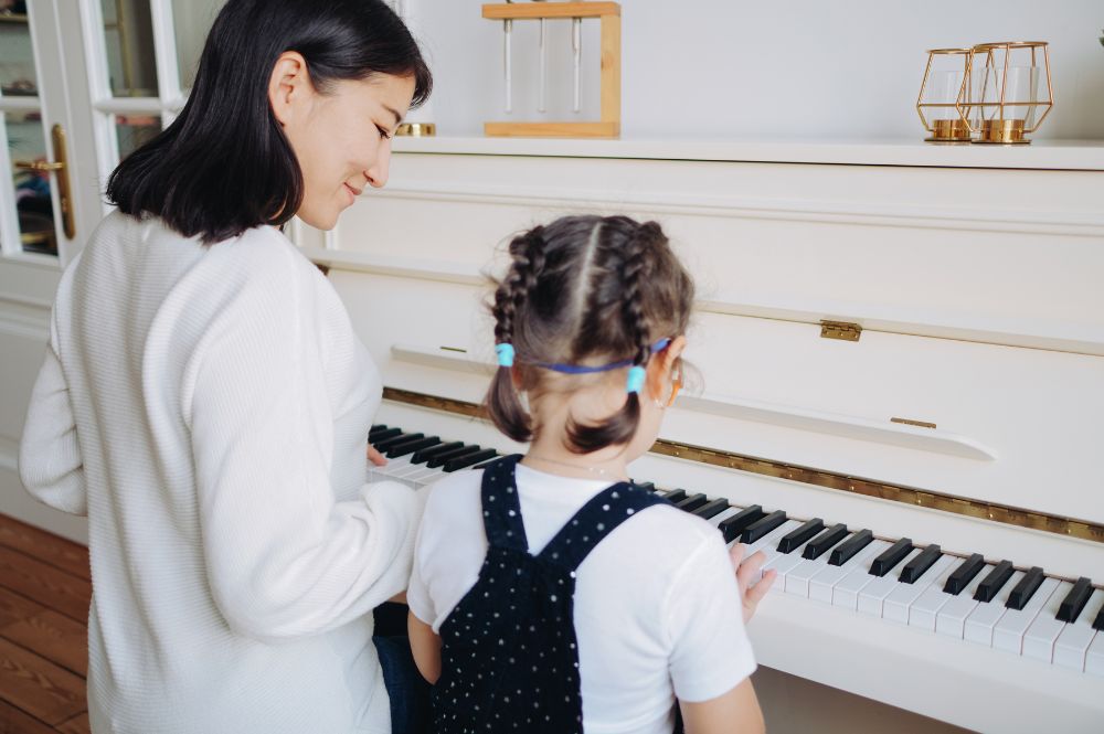woman teaching girl to play piano